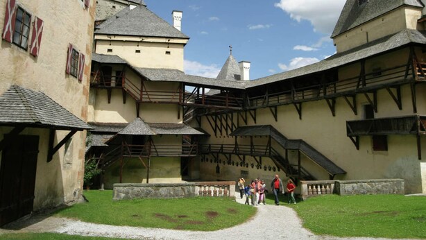 A courtyard with traditional architecture, including a building with a steeply pitched roof and a staircase leading to an upper level. - Modern Apartment in St Margarethen With Mountain View (Sankt Margarethen im Lungau)