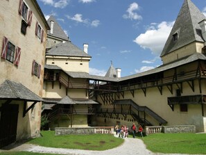 A courtyard with traditional architecture, including a building with a steeply pitched roof and a staircase leading to an upper level. - Modern Apartment in St Margarethen With Mountain View (Sankt Margarethen im Lungau)