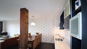 Eine moderne Küche mit Einbauherd, ein Essbereich mit Holztisch und -stühlen sowie ein großes Fenster mit Blick auf die Stadt.