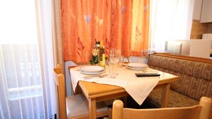 A dining area with a table set for two, a sofa, and a small table with a remote control. - Apartment in Wagrain at the ski Lift (Wagrain)
