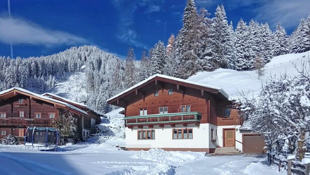A wooden chalet with a balcony, surrounded by snow-covered trees and a clear blue sky. - Apartment in Wagrain at the ski Lift (Wagrain)