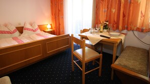 A hotel room with a bed, a dining table with chairs, a small table with a remote control, and a window with curtains. - Apartment in Wagrain at the ski Lift (Wagrain)