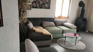 A living room with a green sofa, patterned cushions, a glass coffee table, and a fireplace. - Luxurious Chalet in Habkern With Private Garden (Habkern)