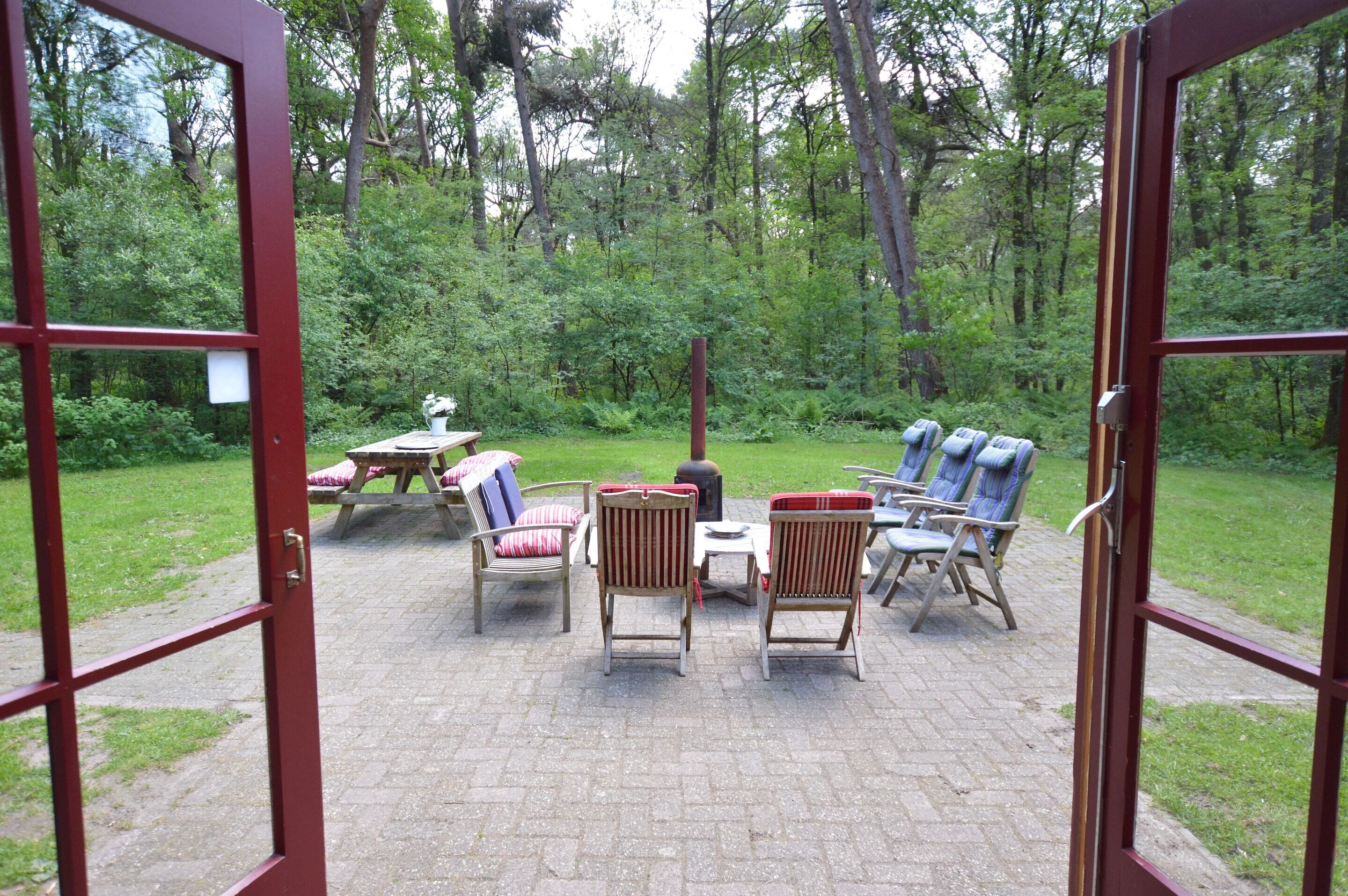 Un patio ouvert, aménagé avec du mobilier d’extérieur, et offrant une vue sur une zone boisée.