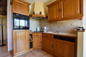 Eine Küche mit Holzausstattung, integriertem Backofen, einer Kaffeemaschine und einem Geschirrspüler.