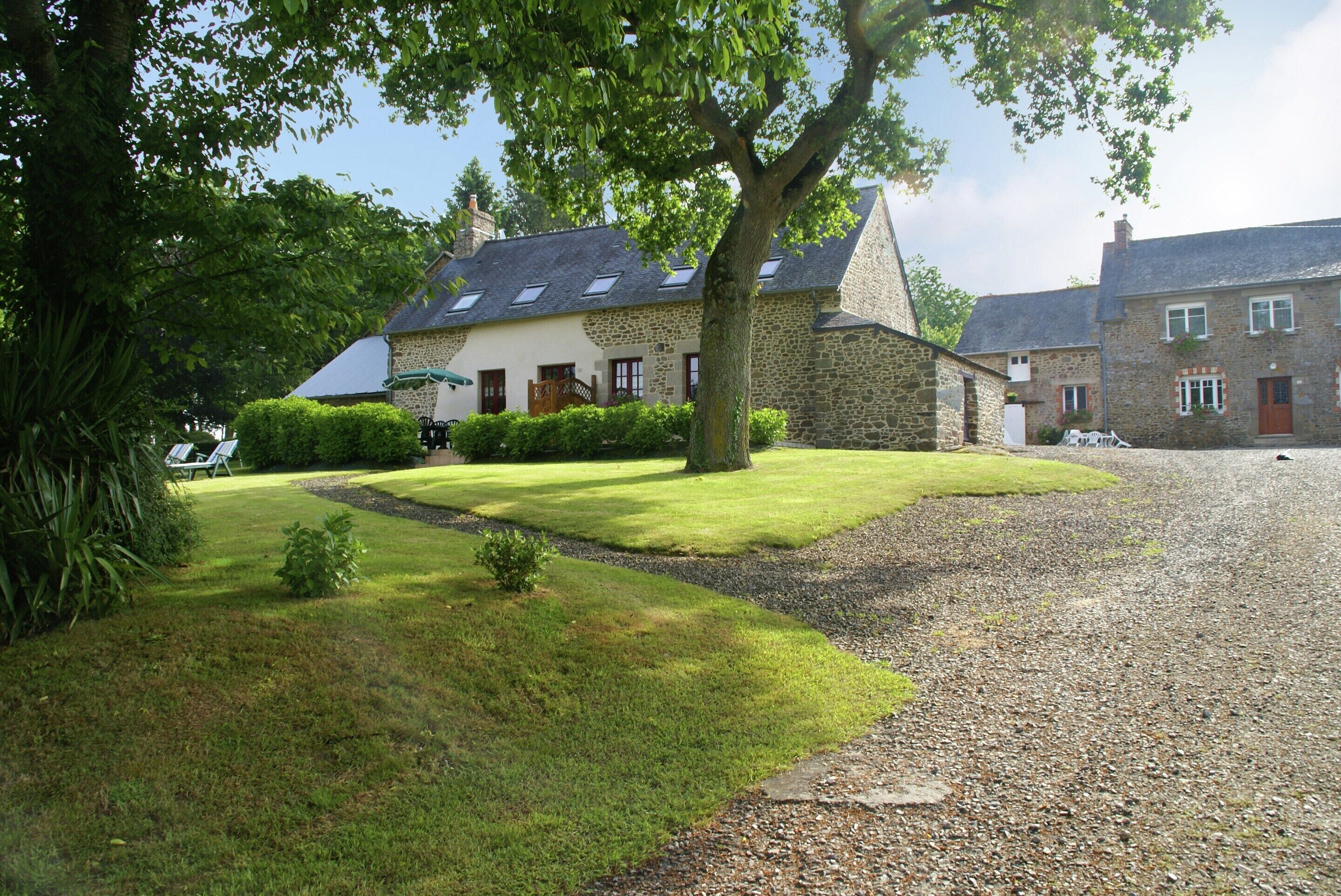 A stone building with a sloped roof, a well-maintained lawn, and a gravel driveway.