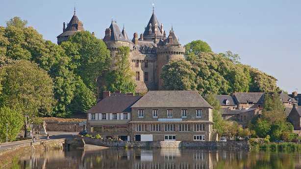 Un edificio histórico con una torre destacada, ubicación junto al río, y un edificio con la leyenda 'HOTEL RESTAURANT FRANCI'.