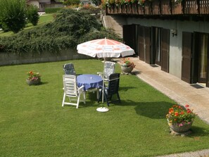 A patio with a table and chairs, a covered umbrella, and potted plants.