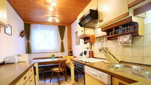 Una cucina compatta con mobili in legno, un tavolo da pranzo con sedie, una finestra con tende e uno schienale piastrellato.