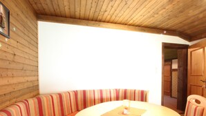 A wooden interior with a round table and striped bench seating. - Spacious Apartment near Ski Area in Mittersill (Mittersill)