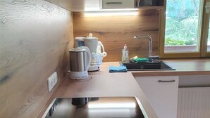A modern kitchen with a built-in stove, a sink, and a window with a view of greenery. - Cosy Apartment in Neukirchen near Krimmler Waterfalls (Neukirchen am Grossvenediger)