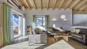 A modern living room with a wooden ceiling, large windows, and a mix of leather and fabric sofas.