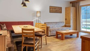 A modern living room with a wooden dining table, two chairs, a sofa, a coffee table, and a lamp. - Chalet in Wald Near Ski Slopes (Wald im Pinzgau)