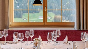 A dining area with a table set for six, three wine glasses on each side, and a vase with flowers on the table. - Chalet in Wald Near Ski Slopes (Wald im Pinzgau)