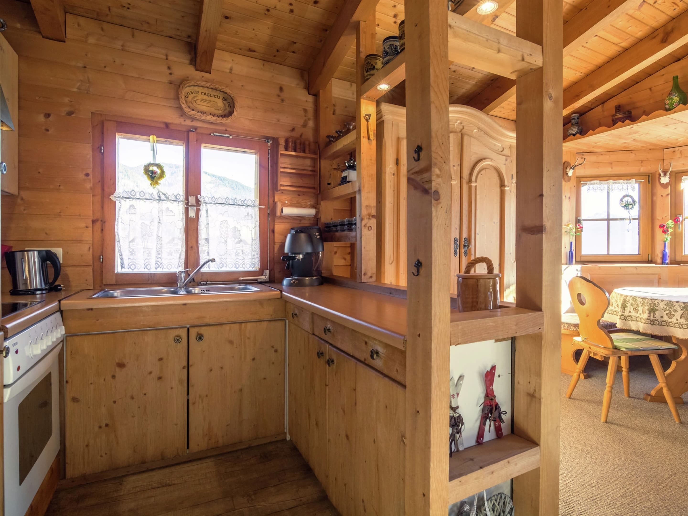 A wooden cabin kitchen with a stove, sink, and coffee maker.