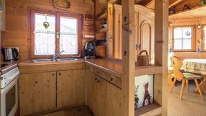 A wooden cabin kitchen with a stove, sink, and coffee maker. - Chalet on the Slopes (Piesendorf)