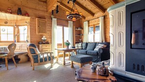 A cozy cabin interior with wooden walls, a sofa, a dining table, and a fireplace. - Chalet on the Slopes (Piesendorf)