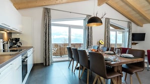 Une cuisine moderne avec un coin repas, de grandes fenêtres et un plafond en bois.