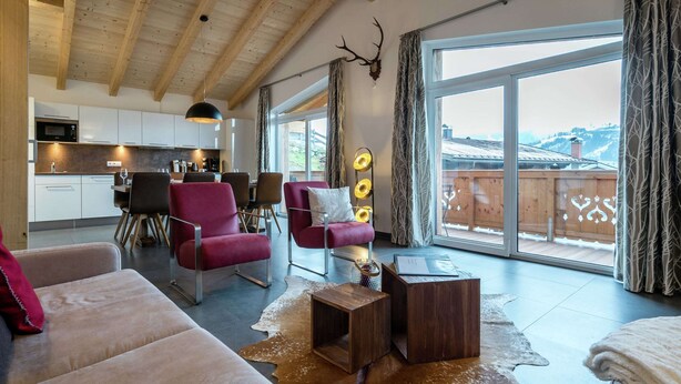 Un salon moderne avec un plafond en bois, un coin repas et une grande porte-fenêtre coulissante donnant sur un balcon.