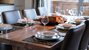 Une table à manger dressée pour un repas, avec des assiettes, des verres et des couverts.
