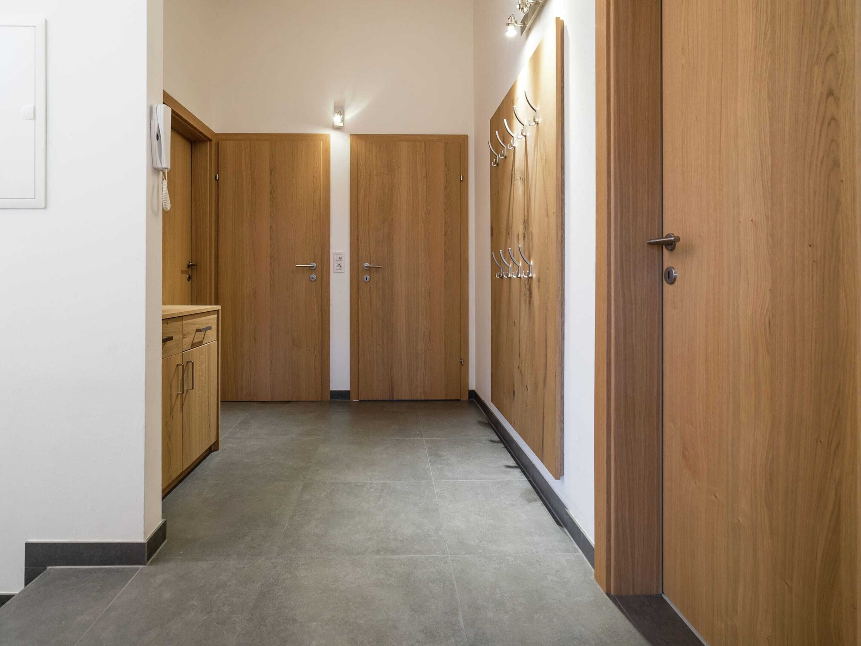 A hallway with wooden doors, a coat rack, and a telephone.