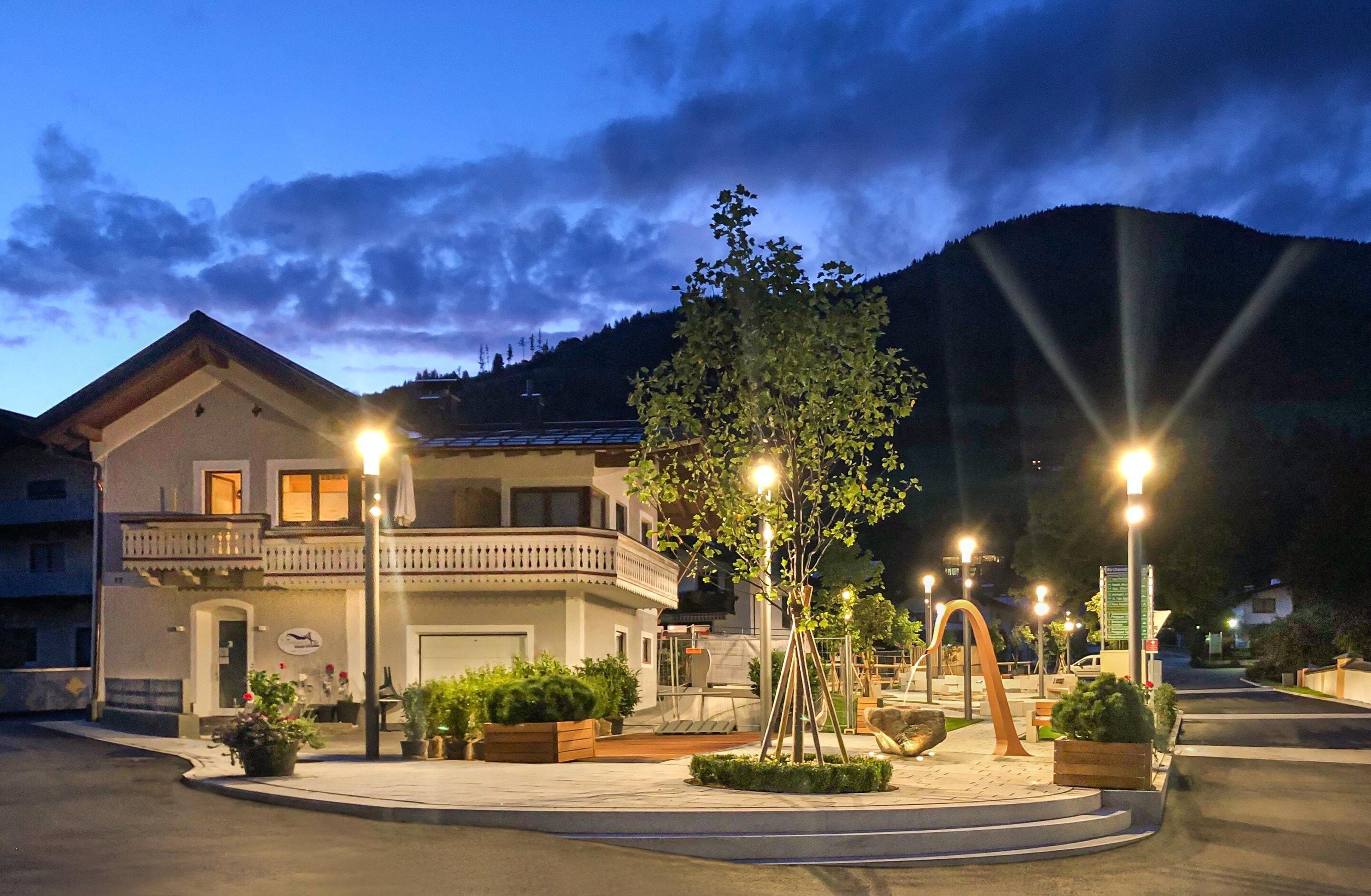 A residential building with a balcony, potted plants, and street lamps.