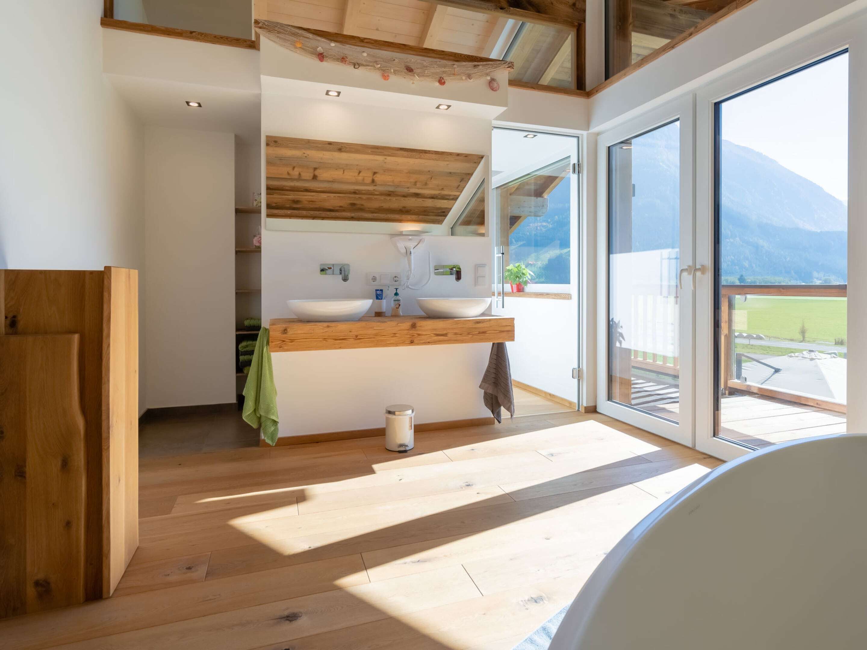 A modern bathroom with a wooden vanity, a large window, and a view of the outdoors.