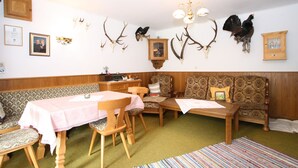 Een kamer met een eettafel, stoelen, een bank en een kamerbreed tapijt.