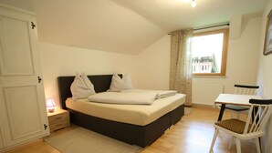 Een slaapkamer met een bed, nachtkastje, stoel en een raam.