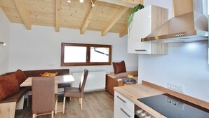 Una cucina compatta con travi in legno, piano cottura integrato e zona pranzo con tavolo e sedie.