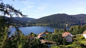 Un lago rodeado de colinas boscosas, con casas en primer plano.