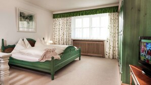 A bedroom with a green bed, a wooden dresser, a radiator, and a television on a wooden cabinet. - Holiday Flat Gastein Near Ski Slopes (Bad Hofgastein)