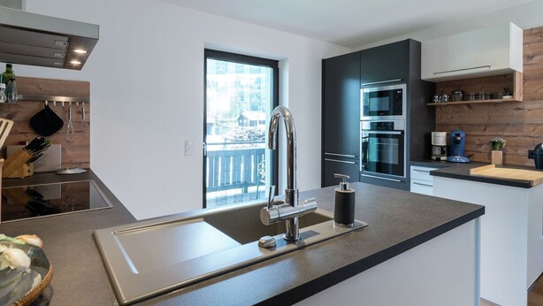 A modern kitchen with a large island, stainless steel appliances, and a view of a snowy landscape. - Spacious Apartment near Ski Area in Niedernsill (Niedernsill)