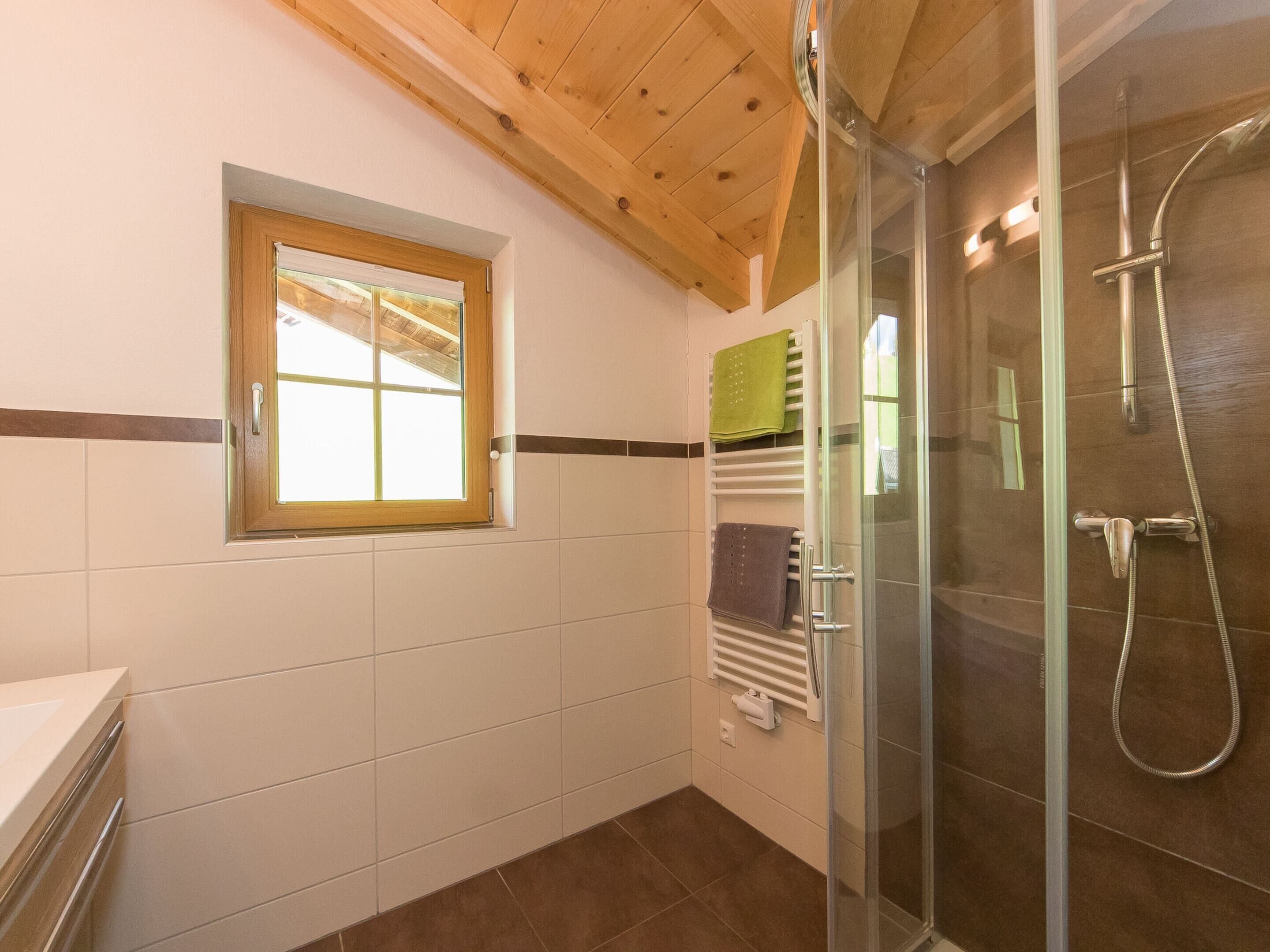 Une salle de bain avec une douche, une fenêtre et un porte-serviettes.