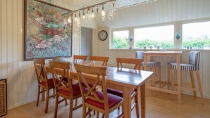 A dining area with wooden tables and chairs, a large fish mural, a chandelier, and a view through the windows. - Waterfront Stelp Farmhouse With Sauna (Molkwerum)