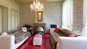 A living room with two sofas, a fireplace, a chandelier, and patterned wallpaper. - Waterfront Stelp Farmhouse With Sauna (Molkwerum)