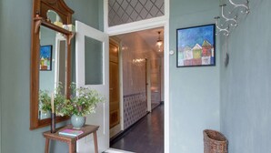 A hallway with a wooden door, a mirror, a vase with flowers, a framed painting, and a wicker basket. - Waterfront Stelp Farmhouse With Sauna (Molkwerum)