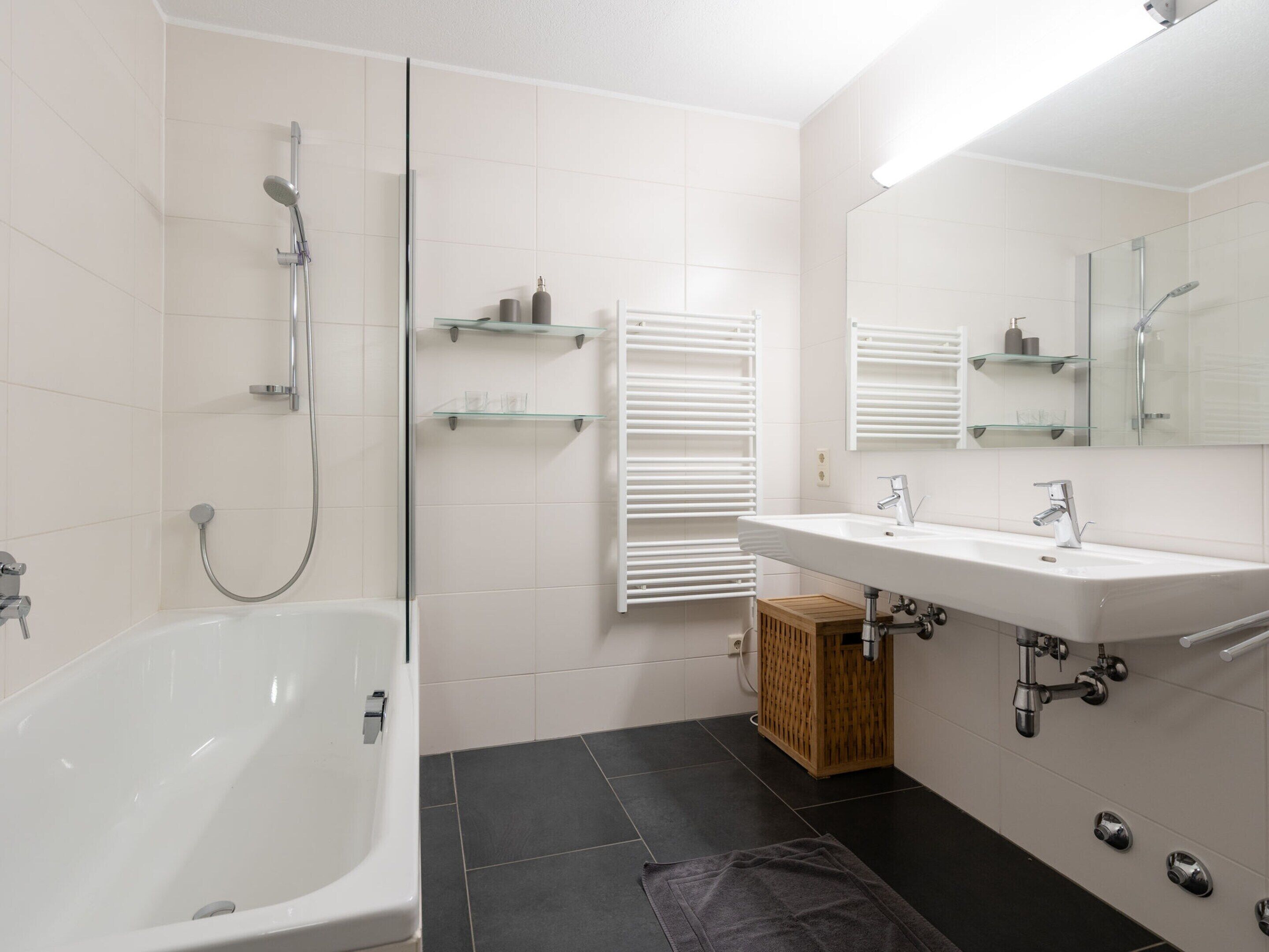 A modern bathroom with a white bathtub, a glass shower enclosure, and a vanity with a mirror.