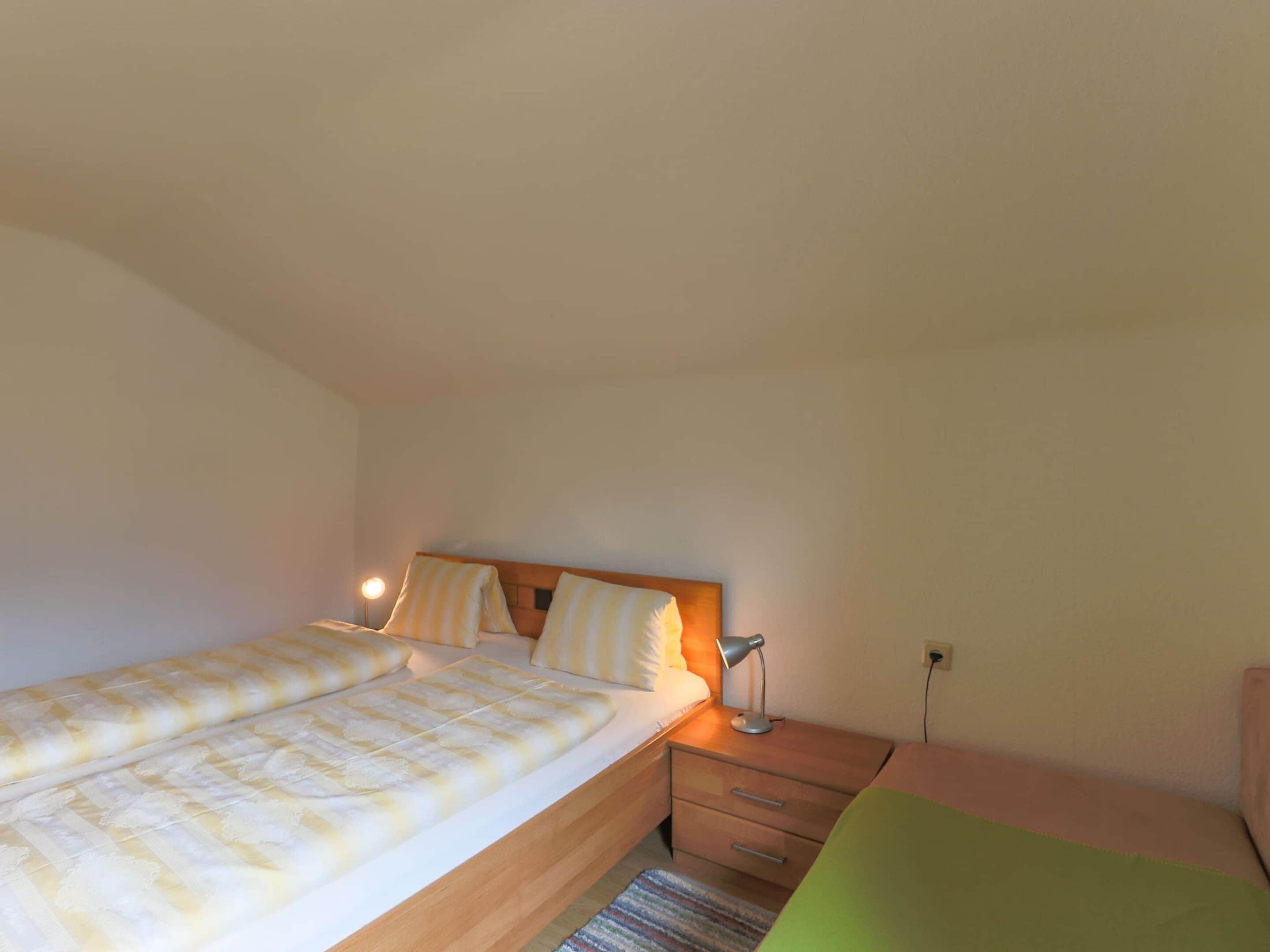 A bedroom with a bed, bedside lamp, and a nightstand.