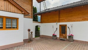 Un bâtiment traditionnel en bois, doté d’un toit en tuiles, d’un balcon en bois et d’une cour également pavée de tuiles.