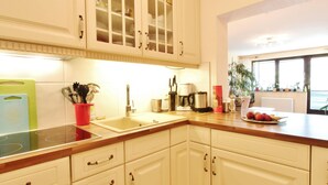 A kitchen with white cabinets, a sink, and a countertop with a coffee maker and a fruit bowl. - Apartment Niedernsill Near Ski Slopes (Niedernsill)