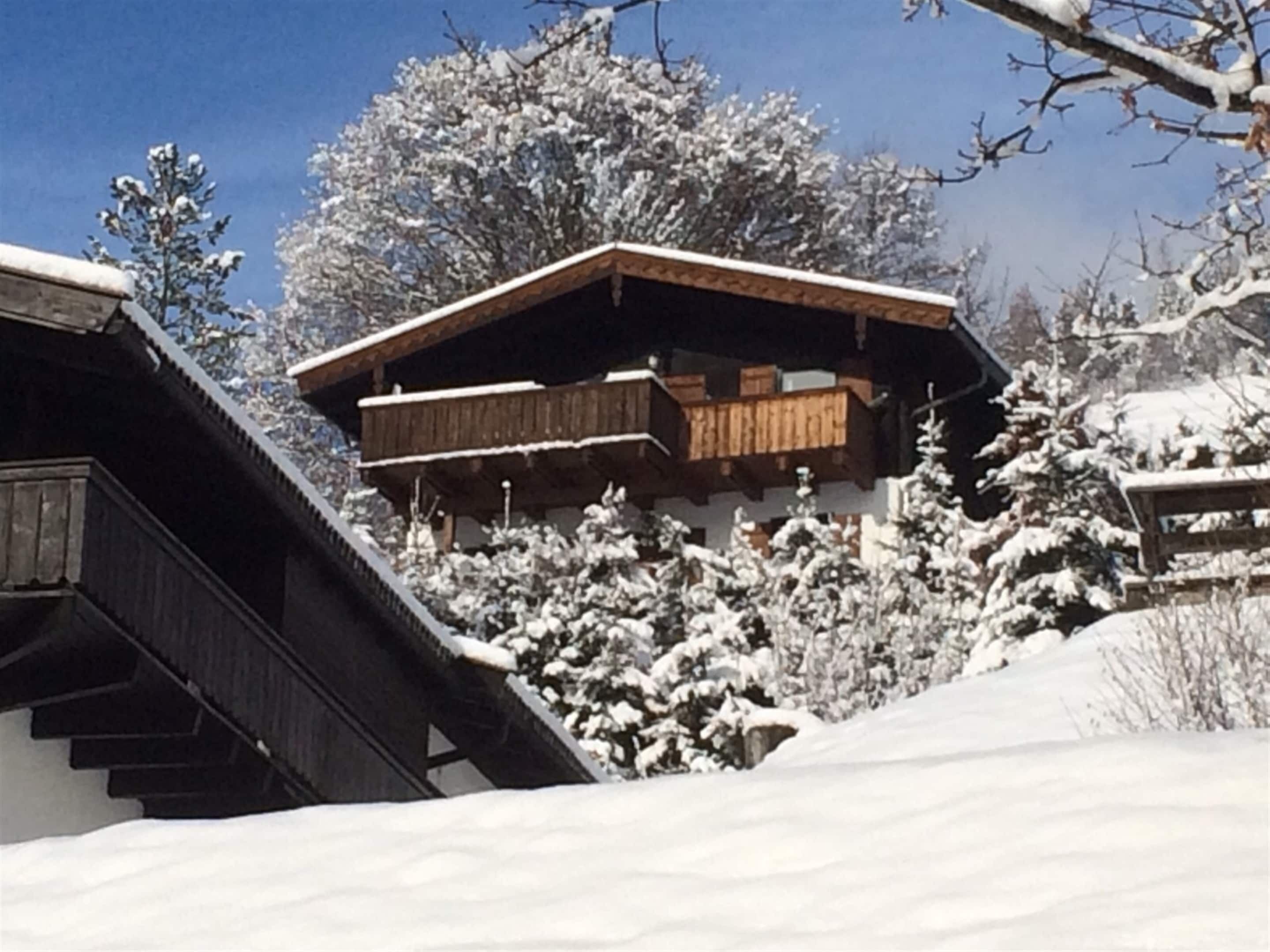 Una cabaña de madera con balcón, rodeada de árboles cubiertos de nieve.