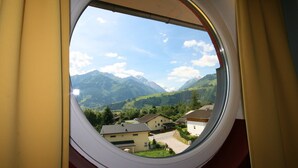 Vista desde una ventana: paisaje montañoso con casas y cielo despejado.