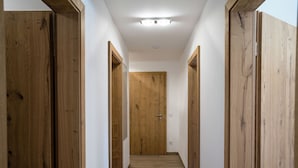 A narrow hallway with wooden doors on both sides and a wooden floor. - Apartment in Hollersbach Near Ski Lift (Hollersbach im Pinzgau)