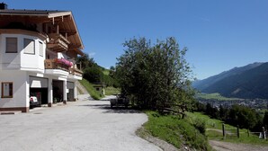 Un bâtiment doté d’un balcon, d’une allée gravillonnée et offrant une vue sur une vallée et des montagnes.