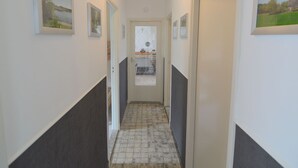 A narrow hallway with white and dark walls, tiled flooring, and framed pictures on the walls. - Holiday Home Koewacht Near Seaside (Koewacht)