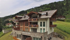 A multi-story residential building with a stone facade, balconies with wooden railings, and a sign reading "RESIDENZ DREI BERGE".
