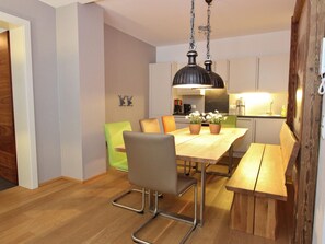 A modern kitchen with wooden flooring, a dining table with chairs, and a hanging light fixture. - Ski In, Ski Out in Saalbach near Zell am See Xpress (Viehhofen)