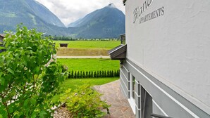 Een gebouw genaamd "Bianca Appartments" met uitzicht op bergen en een groen veld.