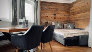 Een moderne kamer met een houten wand, een bed met een zachte deken, een bureau met een stoel en een raam met gordijnen.